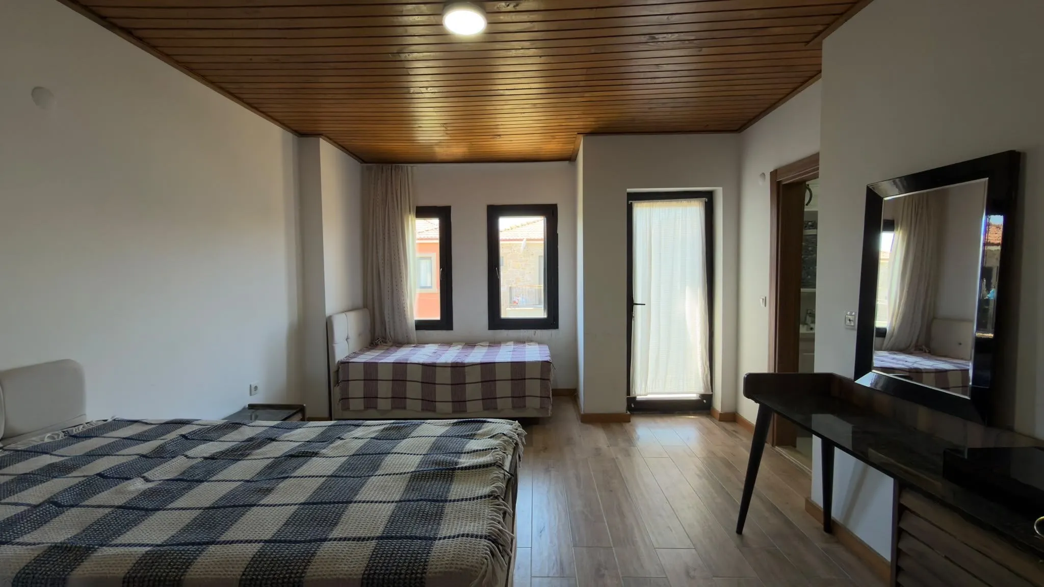 Furnished bedroom with a wooden ceiling, photographed with a phone